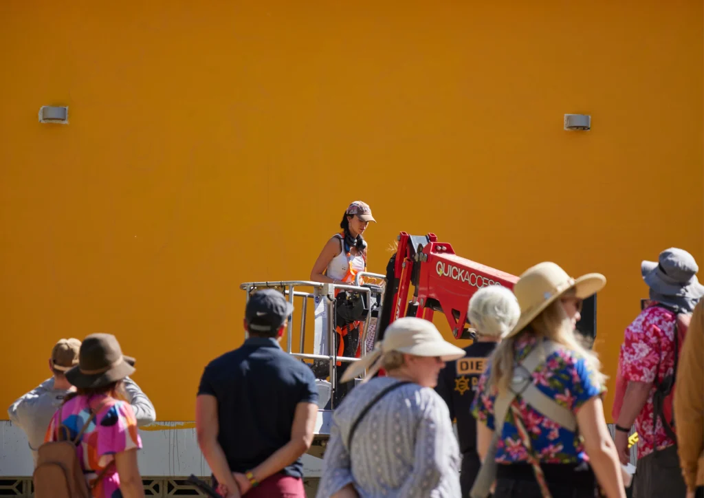 Guided tour group watches artist Minna Leunig produce work at the 2024 Benalla Street Art Festival Photo by Holly Hawkins