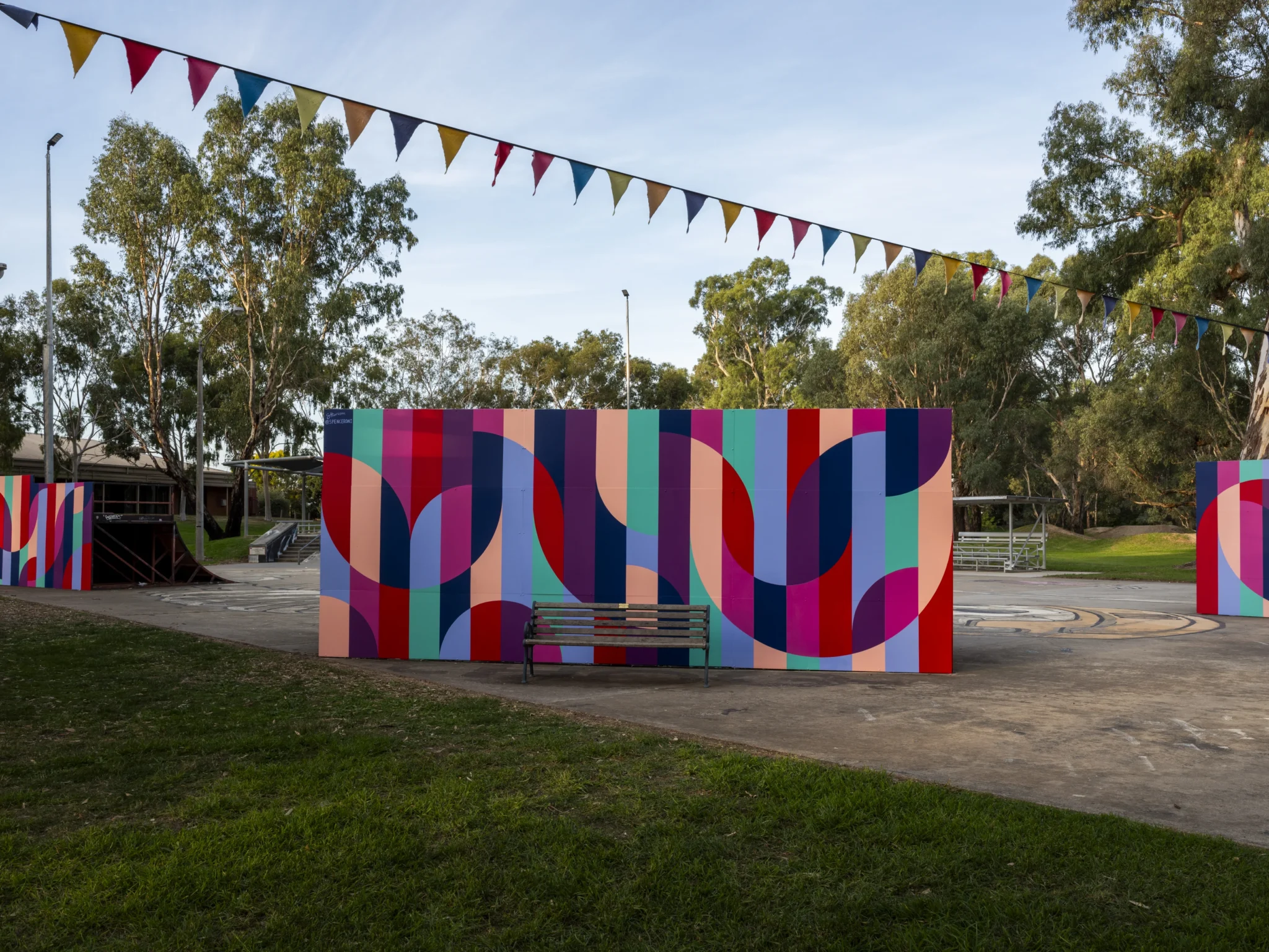 Spencer Harrison’s mural pays tribute to the iconic half-pipe, with sweeping circular forms capturing the energy and movement of skaters soaring through the air. The colours of the design are vibrant and youthful, reflecting the central role the Benalla Skate Park plays for the local youth community. This artwork was part of the 2025 Benalla Street Art Festival.
