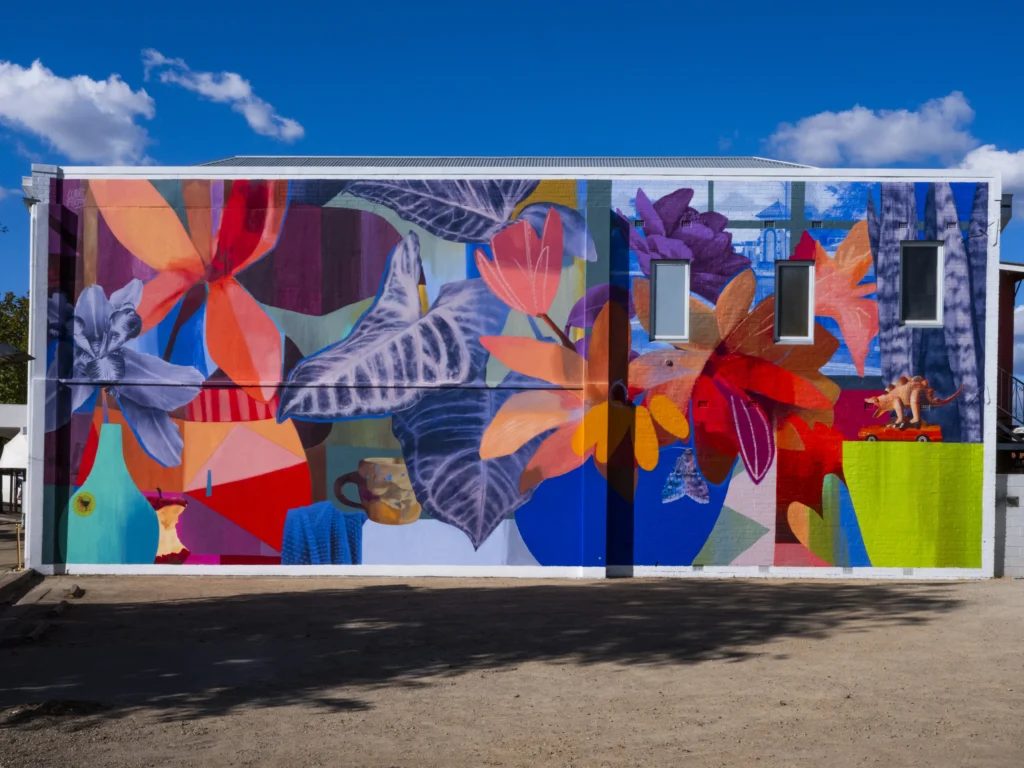This bright, central mural is a collage-inspired still life that celebrates humble, everyday moments through bold colour and composition. This artwork was part of the 2025 Benalla Street Art Festival.